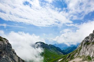 Explore the breathtaking Swiss Alps with lush green valleys and towering peaks under a vibrant sky.