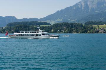 Passenger ferry cruising on Lake Lucerne with stunning Swiss Alps backdrop.